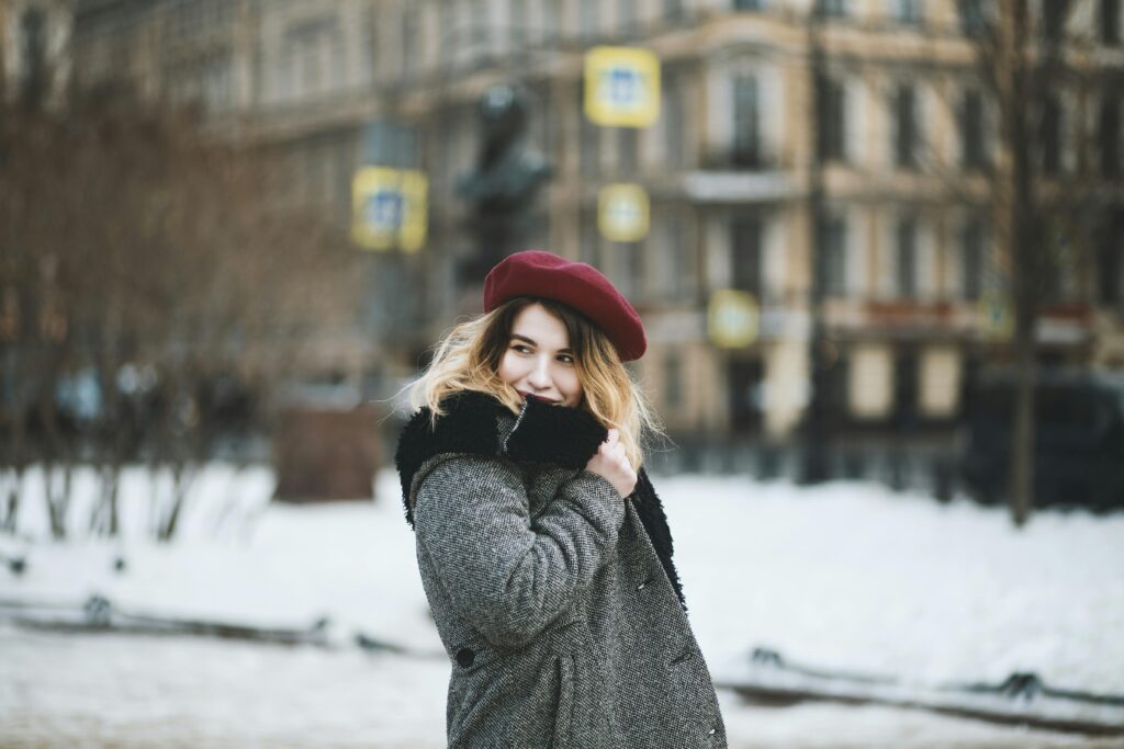 pexels-photo-1381549-1381549 A young woman in a stylish coat and beret poses on a snowy street, capturing urban winter fashion.